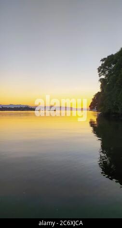 Sonnenaufgang Sonnenuntergang am Fluss 'Canal do estuário', zwischen den Städten Guaruja und Bertioga in Brasilien. Farbenfrohe und ruhige Sonnenaufgänge an einem ruhigen Fluss. Stockfoto