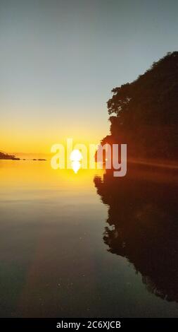 Sonnenaufgang Sonnenuntergang am Fluss 'Canal do estuário', zwischen den Städten Guaruja und Bertioga in Brasilien. Farbenfrohe und ruhige Sonnenaufgänge an einem ruhigen Fluss. Sli Stockfoto