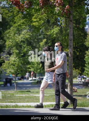 Vancouver, Kanada. Juli 2020. Menschen mit Gesichtsmasken gehen am 12. Juli 2020 in einem Park in Vancouver, British Columbia, Kanada. In der vergangenen Woche ist die Zahl der Neuerkrankungen in British Columbia stetig gestiegen. Am 10. Juli verkündeten die Gesundheitsbehörden der Provinz 25 neue Fälle, die größte Zunahme seit Anfang Mai. Ein UBC-Experte sagt, es gibt eine Möglichkeit, dass B.C. zu Sperrbedingungen zurückkehren könnte, wenn COVID-19 Fallzahlen weiter steigen. Quelle: Liang Sen/Xinhua/Alamy Live News Stockfoto