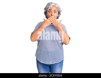 Ältere Frau mit grauen Haaren tragen lässige gestreifte Kleidung schockiert Abdeckung Mund mit Händen für Fehler. Secret Konzept. Stockfoto