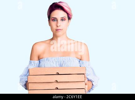Junge schöne Frau mit rosa Haar halten Lieferung Pizza Box Denken Haltung und nüchternen Ausdruck selbstbewusst suchen Stockfoto