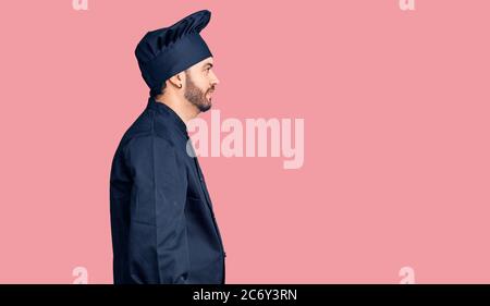 Junge hispanic Mann trägt Herd Uniform suchen zur Seite, entspannen Profil Pose mit natürlichen Gesicht mit selbstbewussten Lächeln. Stockfoto