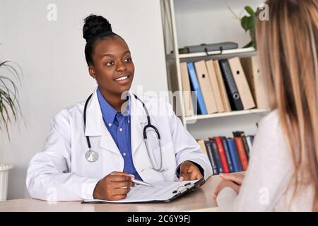 Afrikanischer Arzt Arzt Beratung kaukasischen Frau Patient bei einem medizinischen Besuch. Stockfoto