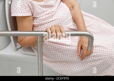 Ältere Frau Holding auf Handlauf in der Toilette. Stockfoto