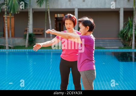 Ältere Frau macht mit Tochter Sport auf der Poolterrasse Stockfoto