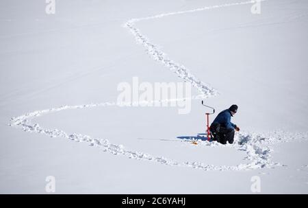 Ein Mann mittleren Alters Eisfischen im Winter, Finnland Stockfoto