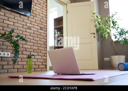 Online-Workout zu Hause Konzept. Laptop-Computer auf Yogamatte auf dem Boden. Stockfoto