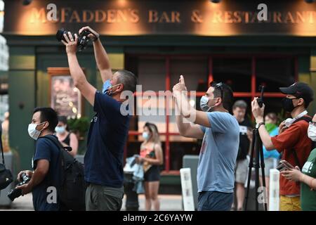 Einige tragen Gesichtsmasken in der Zeit von COVID-19, Menschen mit Kameras Reihe entlang der Median Streifen entlang 42nd Street und Second Avenue warten auf den Sonnenuntergang Phänomen als "Manhattanhenge" bekannt, Die von diesem Ort aus wegen der anhaltenden Sturmwolken am Horizont für eine zweite Nacht in Folge nicht zu sehen war, New York, NY, 12. Juli 2020. Manhattanhenge ist das Ereignis, bei dem die untergehende (oder aufgehende) Sonne perfekt mit den Ost-West-Straßen des Manhattan Island Street Grid übereinstimmt, das zweimal im Jahr stattfindet. (Anthony Behar/Sipa USA) Stockfoto