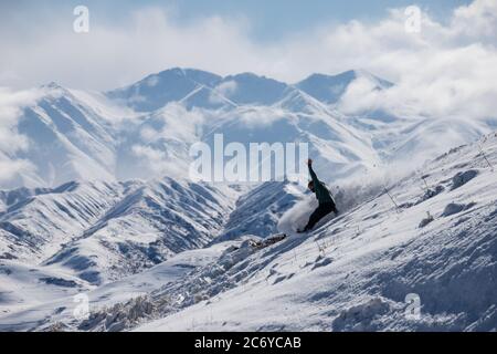 Ein eineinesiger Snowboarder schnitzt während einer Wintertour einen Hügel im Chuy-Gebiet von Kirgisistan hinunter. Stockfoto