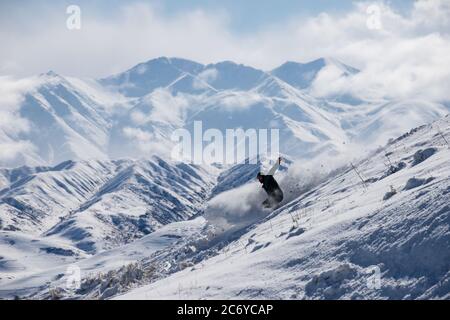 Ein eineinesiger Snowboarder schnitzt während einer Wintertour einen Hügel im Chuy-Gebiet von Kirgisistan hinunter. Stockfoto