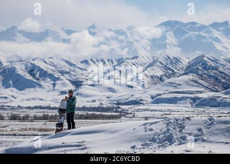 Ein eineinesiger Snowboarder schnitzt während einer Wintertour einen Hügel im Chuy-Gebiet von Kirgisistan hinunter. Stockfoto