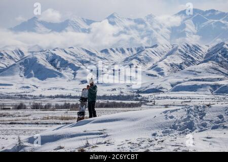 Ein eineinesiger Snowboarder schnitzt während einer Wintertour einen Hügel im Chuy-Gebiet von Kirgisistan hinunter. Stockfoto