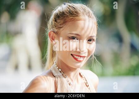 Porträt einer attraktiven jungen vietnamesischen Frau, die in Sonnenstrahlen steht und die Kamera anlächelt Stockfoto