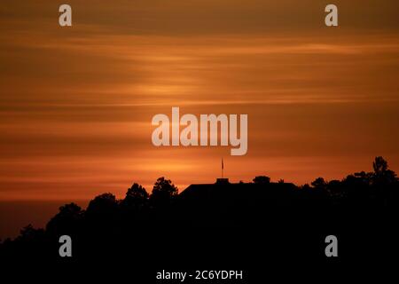 Stuttgart, Deutschland. Juli 2020. Wolken erscheinen kurz vor Sonnenaufgang über Bäumen und dem Dach der Villa Reitzenstein, dem Sitz des baden-württembergischen Staatsministeriums. Quelle: Marijan Murat/dpa/Alamy Live News Stockfoto