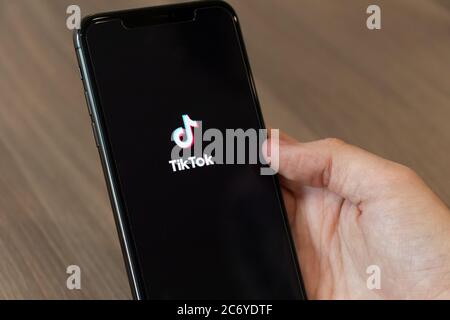 Person, die ein Telefon mit dem TikTok-Logo, der beliebten und umstrittenen chinesischen Video-Sharing-App auf dem Bildschirm. Stockfoto