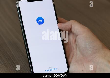 Person, die ein Handy mit der Facebook Messenger-Anwendung auf dem Bildschirm verwendet. Stockfoto