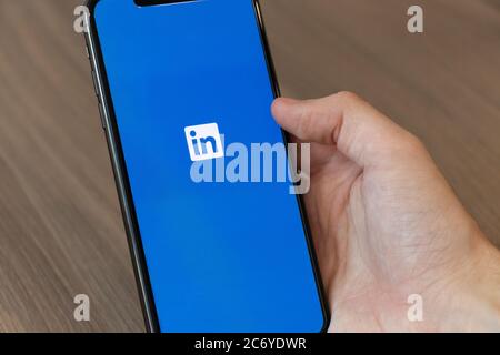 Person, die das Handy mit dem Logo der sozialen Medien LinkedIn-Plattform auf dem Bildschirm nutzt. Stockfoto