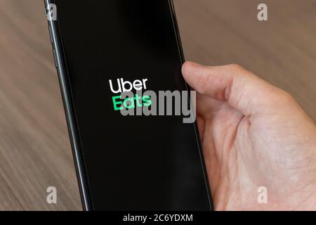 Person, die ein Handy mit dem Uber Eats Logo, dem beliebten Online-Service für die Bestellung und Lieferung von Lebensmitteln, auf dem Bildschirm verwendet. Stockfoto