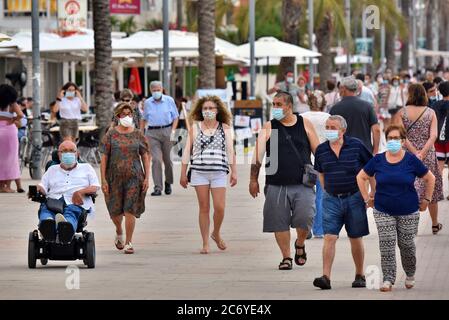 Menschen mit Gesichtsmasken als vorbeugende Maßnahme gehen während der Krise des Coronavirus entlang der Straße Paseo Maritimo.die Regierung von Katalonien hat angekündigt, dass ab Donnerstag eine Geldstrafe von bis zu 100 € (113 USD; £90) wird für Menschen über sechs Jahren, die ihre Häuser ohne Gesichtsmaske verlassen, auch wenn sie einen sicheren Abstand halten berechnet werden, Obwohl die Ausnahmen gemacht werden, wie wenn eine Maske ist "nicht kompatibel" mit einer Aktivität wie Übung, sondern als Ganzes diejenigen, die älter als sechs müssen immer eine Gesichtsbedeckung außerhalb ihres Hauses tragen. Stockfoto