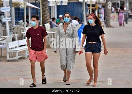 Menschen mit Gesichtsmasken als vorbeugende Maßnahme gehen während der Krise des Coronavirus entlang der Straße Paseo Maritimo.die Regierung von Katalonien hat angekündigt, dass ab Donnerstag eine Geldstrafe von bis zu 100 € (113 USD; £90) wird für Menschen über sechs Jahren, die ihre Häuser ohne Gesichtsmaske verlassen, auch wenn sie einen sicheren Abstand halten berechnet werden, Obwohl die Ausnahmen gemacht werden, wie wenn eine Maske ist "nicht kompatibel" mit einer Aktivität wie Übung, sondern als Ganzes diejenigen, die älter als sechs müssen immer eine Gesichtsbedeckung außerhalb ihres Hauses tragen. Stockfoto