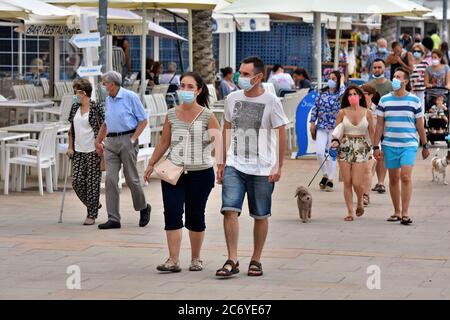 Menschen mit Gesichtsmasken als vorbeugende Maßnahme gehen während der Krise des Coronavirus entlang der Straße Paseo Maritimo.die Regierung von Katalonien hat angekündigt, dass ab Donnerstag eine Geldstrafe von bis zu 100 € (113 USD; £90) wird für Menschen über sechs Jahren, die ihre Häuser ohne Gesichtsmaske verlassen, auch wenn sie einen sicheren Abstand halten berechnet werden, Obwohl die Ausnahmen gemacht werden, wie wenn eine Maske ist "nicht kompatibel" mit einer Aktivität wie Übung, sondern als Ganzes diejenigen, die älter als sechs müssen immer eine Gesichtsbedeckung außerhalb ihres Hauses tragen. Stockfoto