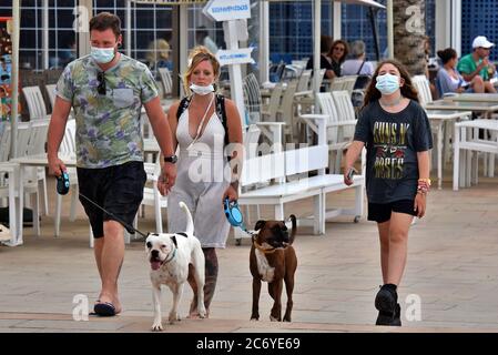 Menschen mit Gesichtsmasken als vorbeugende Maßnahme gehen während der Krise des Coronavirus entlang der Straße Paseo Maritimo.die Regierung von Katalonien hat angekündigt, dass ab Donnerstag eine Geldstrafe von bis zu 100 € (113 USD; £90) wird für Menschen über sechs Jahren, die ihre Häuser ohne Gesichtsmaske verlassen, auch wenn sie einen sicheren Abstand halten berechnet werden, Obwohl die Ausnahmen gemacht werden, wie wenn eine Maske ist "nicht kompatibel" mit einer Aktivität wie Übung, sondern als Ganzes diejenigen, die älter als sechs müssen immer eine Gesichtsbedeckung außerhalb ihres Hauses tragen. Stockfoto