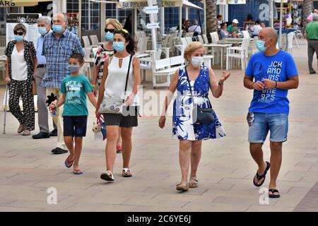 Menschen mit Gesichtsmasken als vorbeugende Maßnahme gehen während der Krise des Coronavirus entlang der Straße Paseo Maritimo.die Regierung von Katalonien hat angekündigt, dass ab Donnerstag eine Geldstrafe von bis zu 100 € (113 USD; £90) wird für Menschen über sechs Jahren, die ihre Häuser ohne Gesichtsmaske verlassen, auch wenn sie einen sicheren Abstand halten berechnet werden, Obwohl die Ausnahmen gemacht werden, wie wenn eine Maske ist "nicht kompatibel" mit einer Aktivität wie Übung, sondern als Ganzes diejenigen, die älter als sechs müssen immer eine Gesichtsbedeckung außerhalb ihres Hauses tragen. Stockfoto