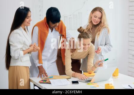 Junge multiethnische Gruppe von Mitarbeitern, Manager von kreativen Unternehmen Blick auf Bildschirm von Laptop zusammen Stockfoto