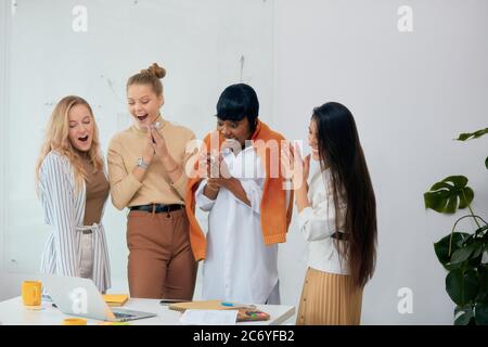 Überraschte Frauen in Freizeitkleidung im Büro zusammen, in Schock mit geöffnetem Mund. Feiern Sie ihren Sieg in Business-Projekt, gute Arbeit der vielfältigen weiblichen Stockfoto