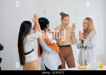Gute Arbeit von vier verschiedenen weiblichen Arbeiten an Business-Projekt, feiern ihren Erfolg im Büro, Laptop auf dem Tisch. White Office Hintergrund Stockfoto