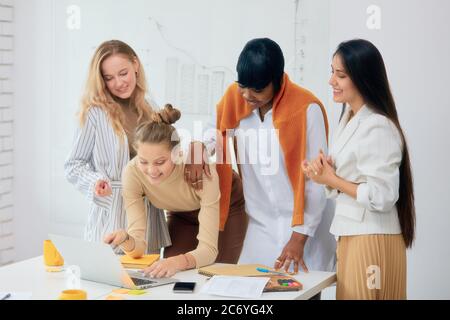 Schöne Frauen im Büro diskutieren gemeinsam neues Projekt mit Laptop, tragen lässige Kleidung, afrikanische und kaukasische Frau zusammen Stockfoto