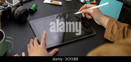Zugeschnittene Aufnahme der weiblichen Designerzeichnung auf einem digitalen Tablet mit Stylus-Stift auf einem Arbeitstisch mit Malwerkzeugen Stockfoto