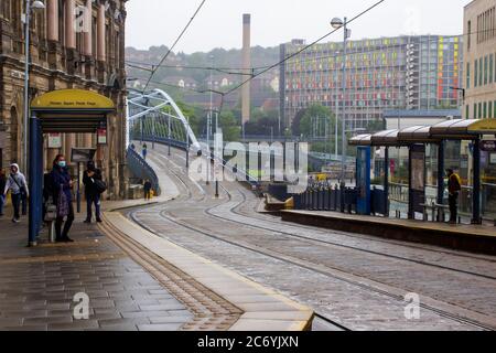 Juli 2020. Ein Blick auf den steilen Hügel auf der Commercial Street Sheffield an einem trüben nassen Tag, mit der Bow Bridge über den Park Square und den Straßenbahnlinien Stockfoto