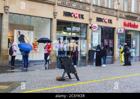 8. Juli 2020 Kunden halten an sozialer Distanz fest, während sie im Regen vor der HSBC Bank-Niederlassung in Fargate Sheffield City Centre England anstehen Stockfoto