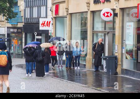 8. Juli 2020 Kunden halten an sozialer Distanz fest, während sie im Regen vor der HSBC Bank-Niederlassung in Fargate Sheffield City Centre England anstehen Stockfoto