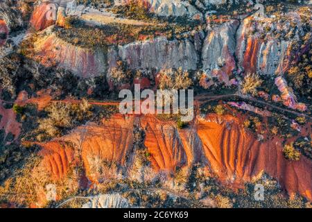 Gant, Ungarn - Luftaufnahme der verlassenen Bauxit-Mine mit warmen roten und orangen Farben und Bäumen bei Sonnenuntergang. Rote Bauxit-Textur Stockfoto