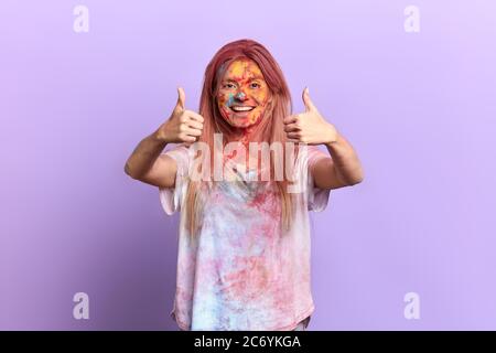 Aufgeregt positive zufriedene Mädchen jubeln auf dem Farbfestival. Nahaufnahme Porträt, isoliert violetten Hintergrund, Studio shot.Gesture, Symbol, Körper lang