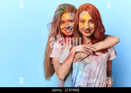 Schöne fröhlich blonde Mädchen umarmt ihren Ingwer Freund und Blick auf die Kamera. Nahaufnahme Foto. Isolierte blauen Hintergrund, Studio-Aufnahme. Frauen fahren Stockfoto