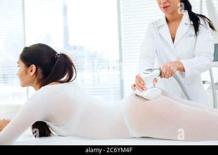 Weibliche Patient liegt auf medizinische Tabelle im Flüssiggasbetrieb entsprechen, die sich zu Fett und cellulite Reduktion. Schönheit LPG Massage Therapie bietet ausgezeichnete Resultat Stockfoto