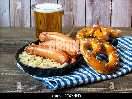 Oktoberfest-Konzept. Traditionelle deutsche Bratwurst mit Sauerkraut, Bier und Brezeln Stockfoto