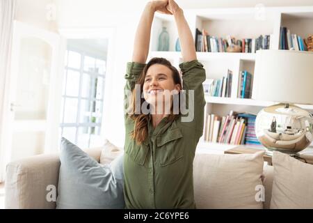 Frau streckt ihre Arme, während sie auf der Couch sitzt Stockfoto