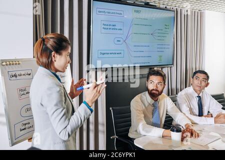 Seriöse Geschäftsleute, die an Meetings teilnehmen und Kollegen zuhören, die über die Möglichkeiten der Unternehmensentwicklung während der Wirtschaftskrise sprechen Stockfoto