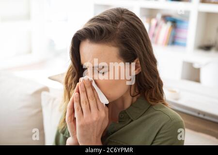 Frau, die zu Hause ihre Nase bläst Stockfoto