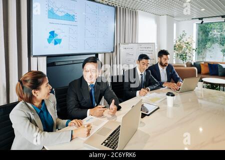 Die Firmenmanager treffen sich am großen Bürotisch und diskutieren Pläne der Unternehmensentwicklung während der Wirtschaftskrise durch covid-19 Pandemie verursacht Stockfoto