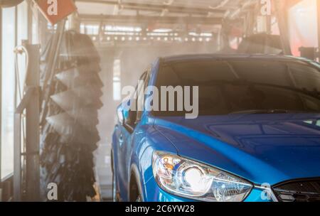 Blaue SUV Auto Waschen mit automatischer Auto-Waschmaschine. Automatische Pflege. Auto Reinigung mit Hochdruck-Wasser-Spray nach der Reinigung mit Auto-Bürste. Reinigung des Autos Stockfoto