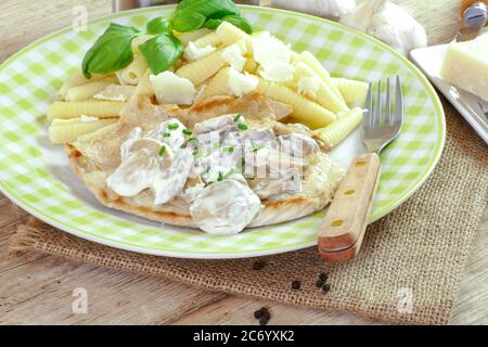 Teller mit Nudeln und Hühnerschnitzel mit Pilzsauce Stockfoto