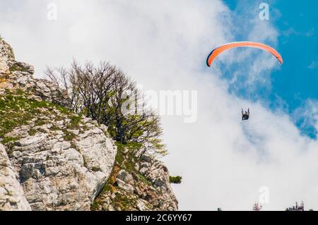 Extreme Erholung, Fallschirmspringer fliegt über die Berge und Felsen. Weiße Wolken am Himmel Stockfoto