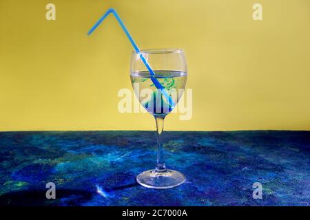 Blauer Cocktail in Weinglas auf gelbem und blauem Hintergrund. Stockfoto