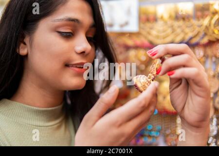 Nahaufnahme der schönen glücklichen Mädchen Kauf Ohrringe im Juwelier. Drehort Sarojini Nagar, Delhi, Indien. Stockfoto