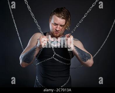 Foto eines tätowierten brutalen Mannes, der in Ketten gebunden ist Stockfoto